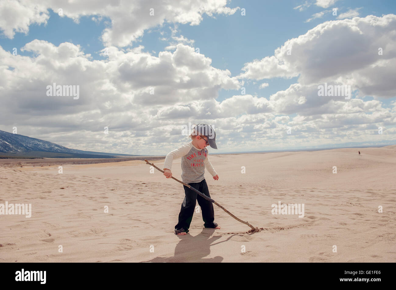Boy writing in sand with stick, Grand Sand Dunes National Park, Colorado, United States Stock Photo