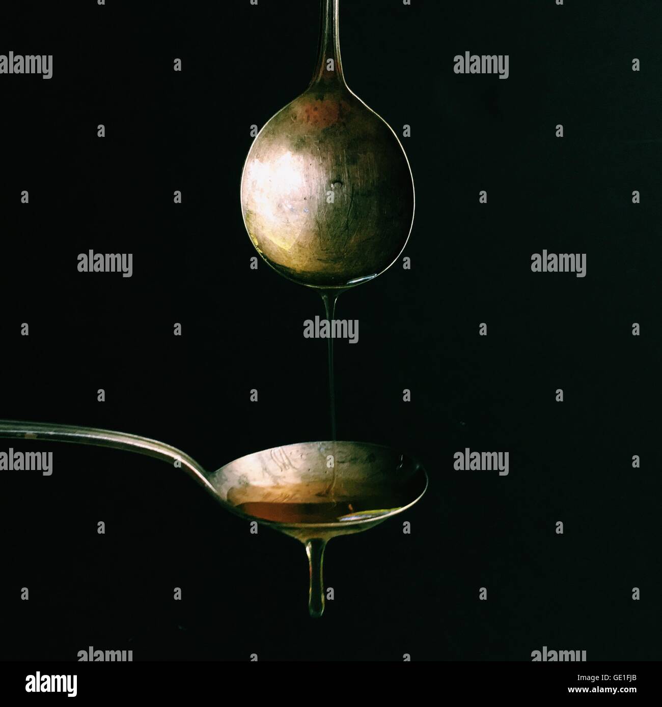 Dripping oil from one spoon onto another Stock Photo