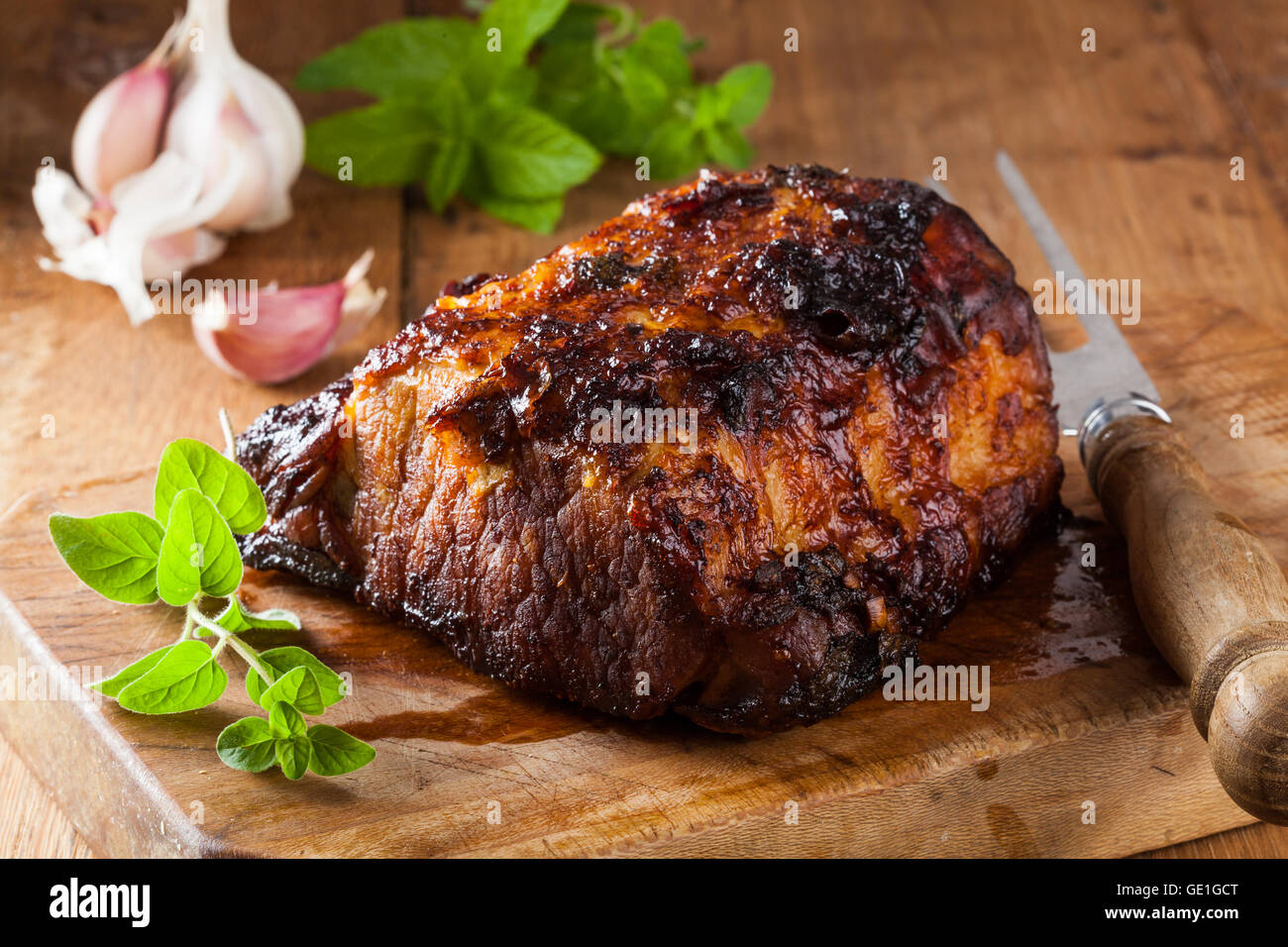 Oven roasted pork loin on a cutting board in a rustic kitchen. Stock Photo