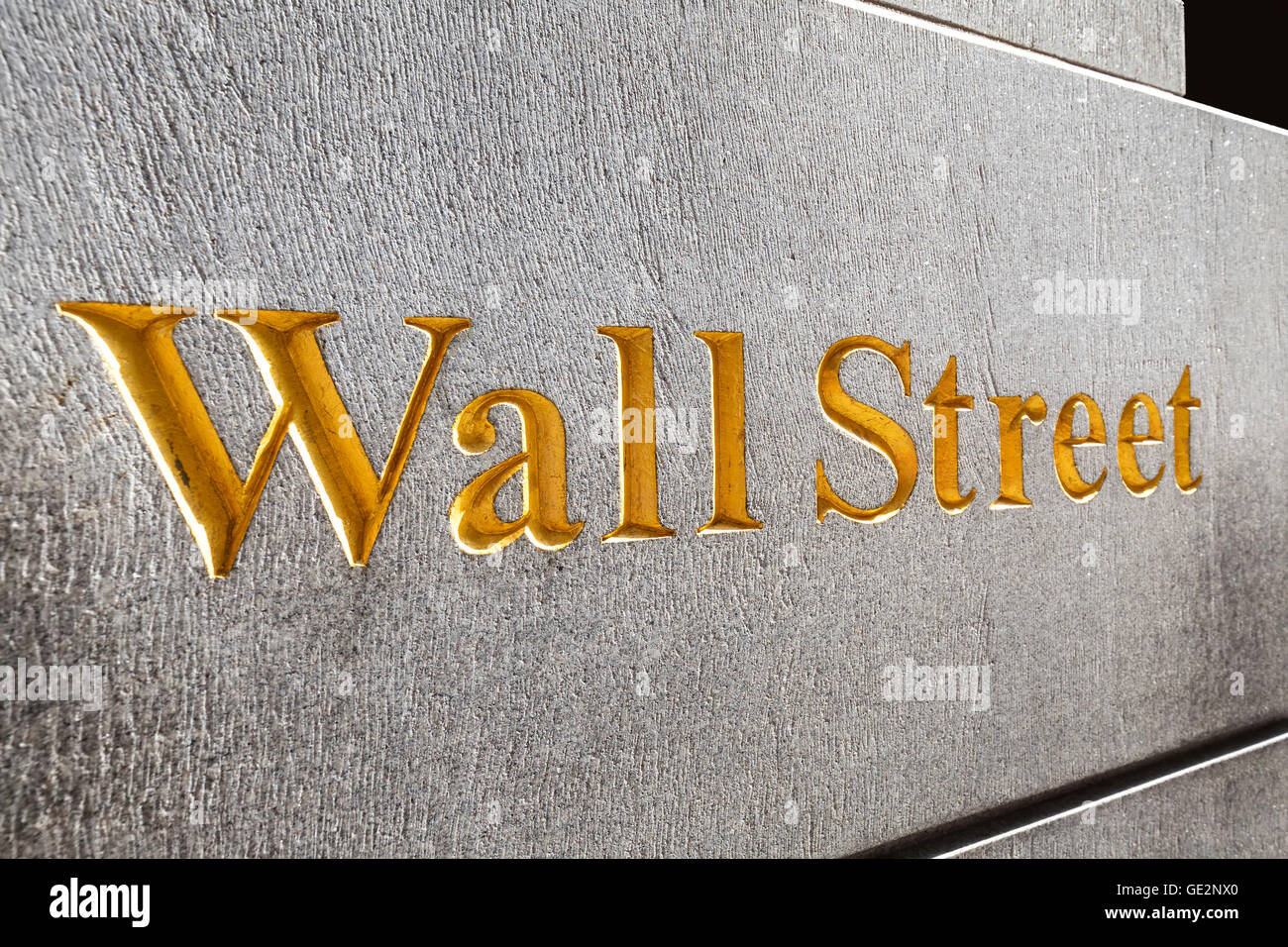 New York, USA - September 13, 2015: Wall Street golden inscription on a building gray stone wall, shallow depth of field. Stock Photo