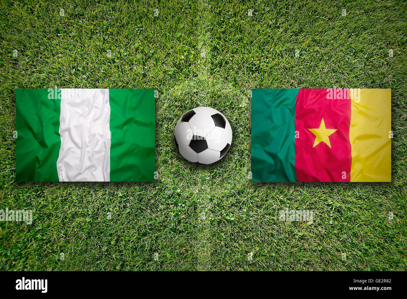 Nigeria vs. Cameroon flags on green soccer field Stock Photo