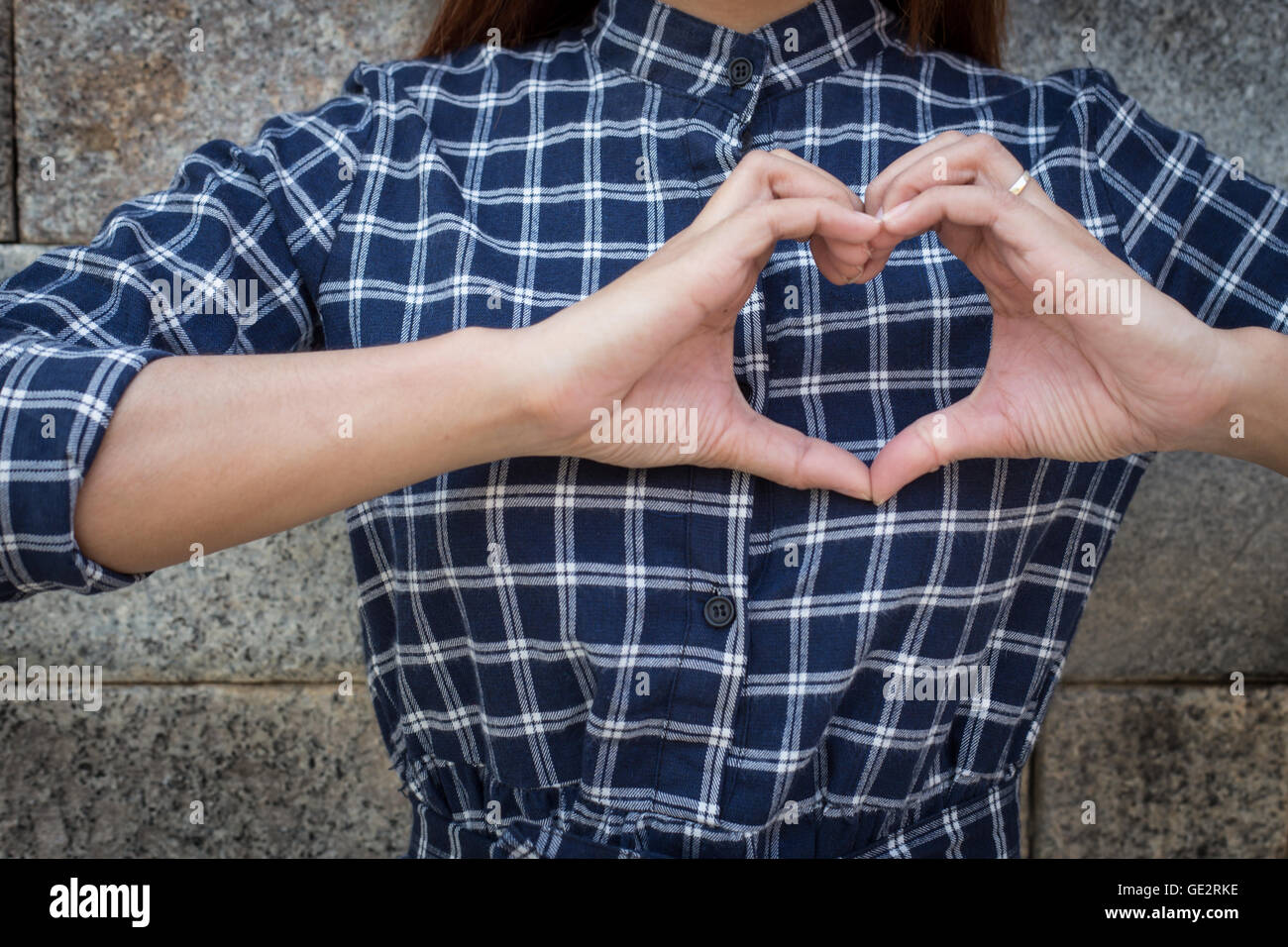 Woman holds heart shape on own. Love emotion (focus shirt) Stock Photo