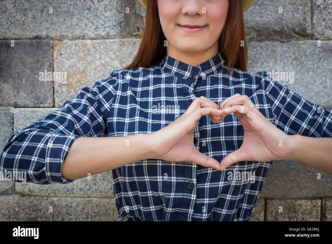 smile woman holds heart shape on own. Love emotion (focus shirt) Stock Photo