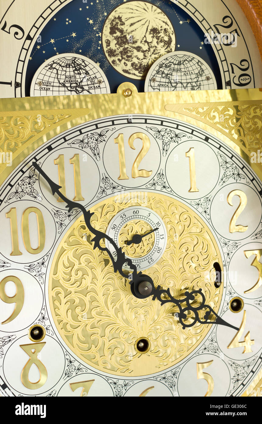 ornate brass engraved grandfather clock face with arabic numerals and moon phase dial Stock Photo