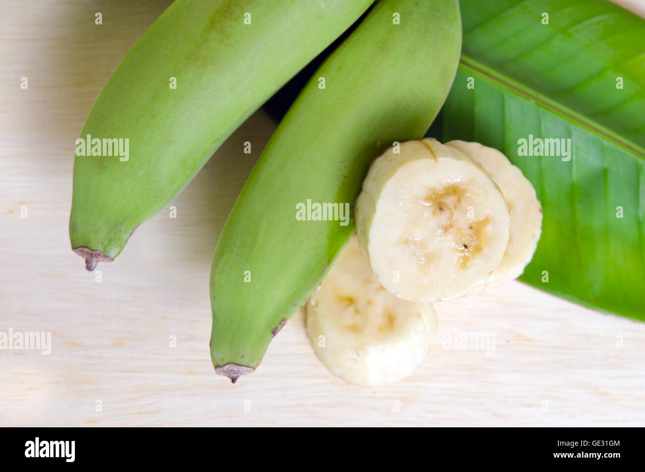 Banana (Other names are Musa acuminata, Musa balbisiana banana, and Musa x paradisiaca) fruit with banana leaf on wood board Stock Photo
