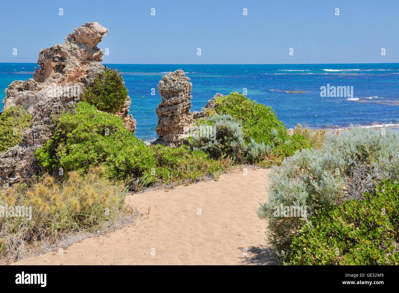 Sandy path through the rough coastal limestone and native plants at Point Peron with Indian Ocean seascape in Western Australia. Stock Photo