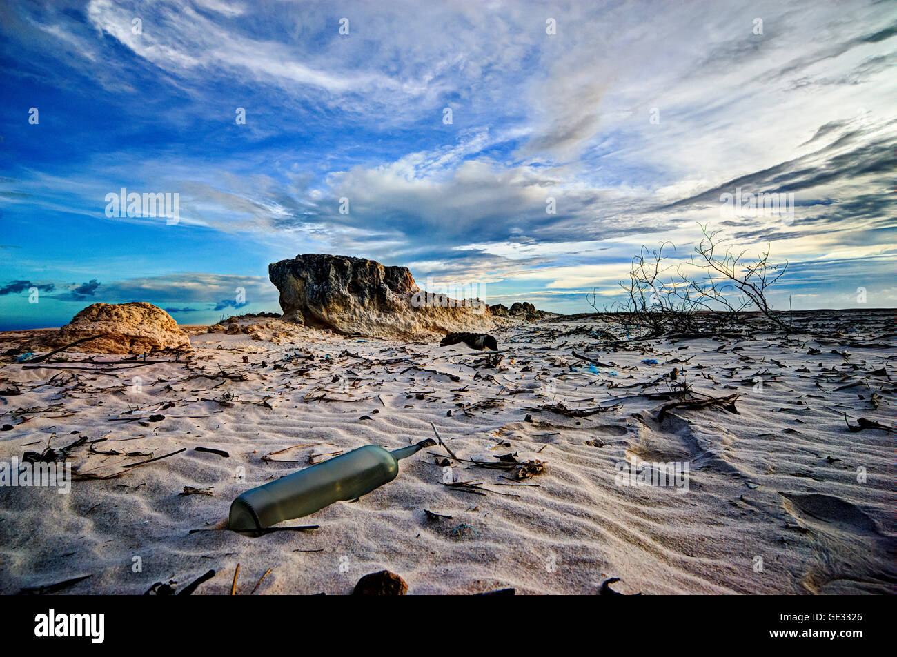 Desert scenery in National Park of Lencois Maranhenses, Brazil. Empty bottle in the foreground and wind sculptered sand rocks Stock Photo