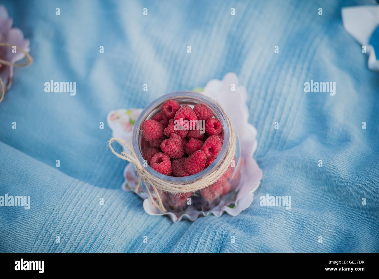 Delicious red raspberries laying in a small jar during picnic in park outdoors Stock Photo