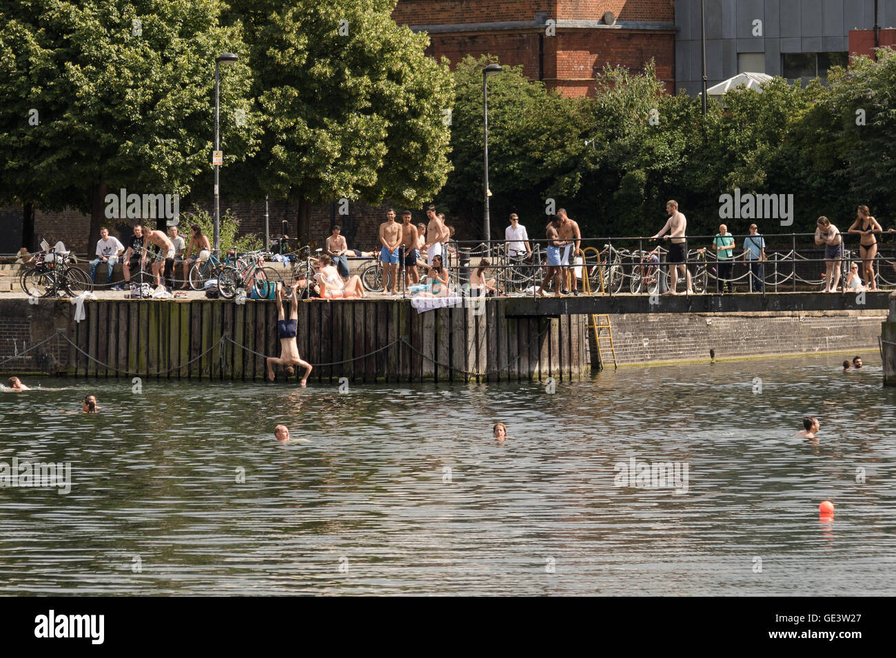 People enjoying the cold water during hot sunny weather at Shadwell Basin in east London this afternoon. People have been warned not to swim in Shadwell Basin after a man drowned and died this week. Stock Photo