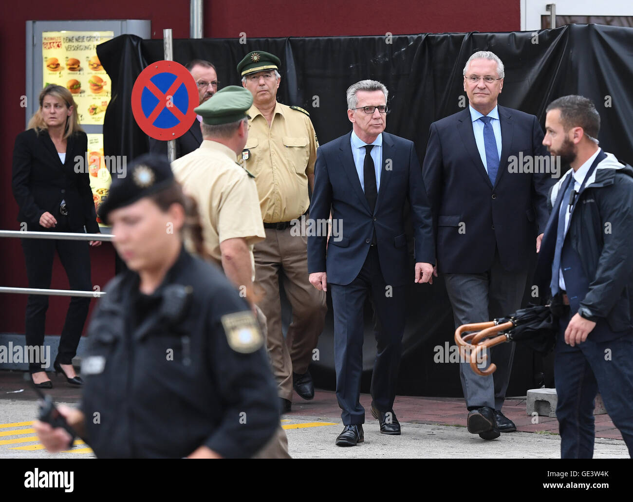 Munich, Germany. 23rd July, 2016. German Interior Minister Thomas de Maiziere (CDU, M) and Bavaria's Interior Minister Joachim Herrmann (CSU, 2.f.R) leave a McDonald's restaurant after inspecting the crime scene near to the Olympia Einkaufszentrum (OEZ), one day after a shooting with deaths and casualties in the building, in Munich, Germany, 23 July 2016. The fatal shooting was carried out by an 18-year-old German-Iranian man. Ten people died, including the perpetrator. Photo: SVEN HOPPE/dpa/Alamy Live News Stock Photo