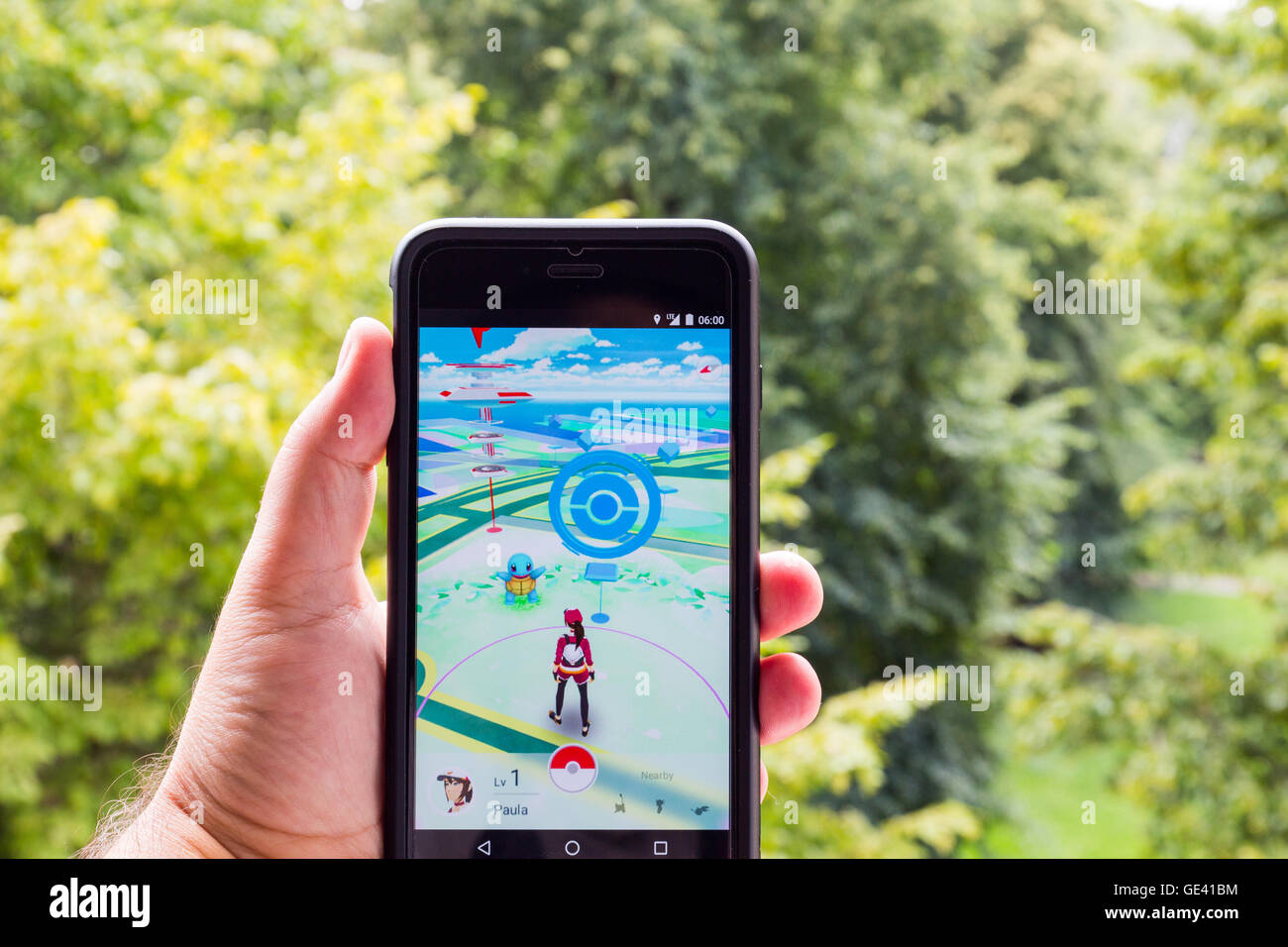 Apple iPhone6 Plus held in one hand showing its screen with Pokemon Go application. Stock Photo