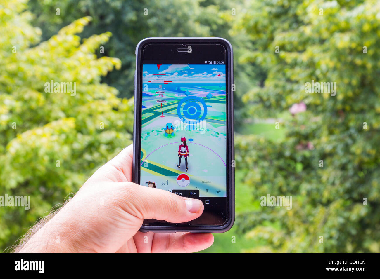 Apple iPhone6 Plus held in one hand showing its screen with Pokemon Go application. Stock Photo