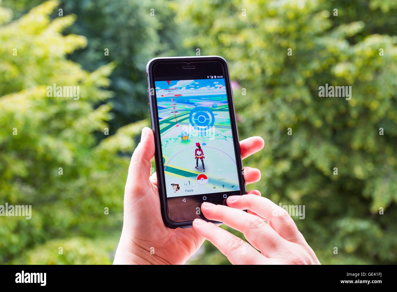 Apple iPhone6 Plus held in one hand showing its screen with Pokemon Go application. Stock Photo