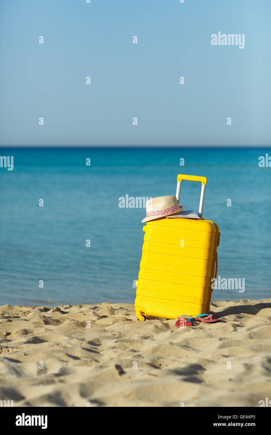 Travel holiday vacation suitcase with map, straw hat and beach slippers on the beautiful sand beach. Advertisement travel suitca Stock Photo