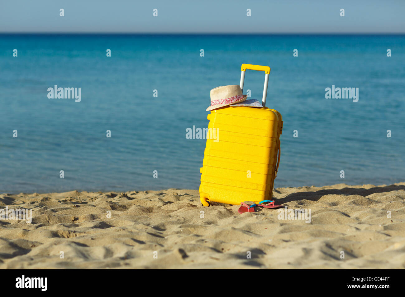 Travel holiday vacation suitcase with map, straw hat and beach slippers on the beautiful sand beach. Advertisement travel suitca Stock Photo