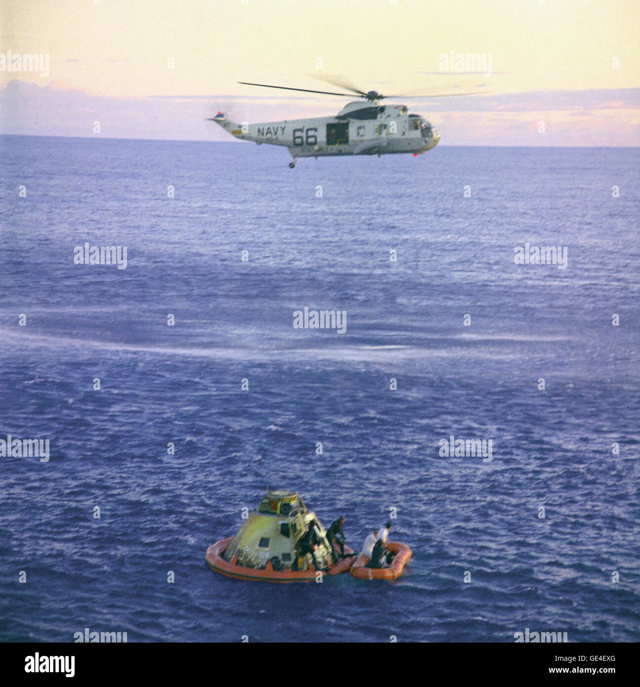 A Navy helicopter arrives to recover the Apollo 10 astronauts, seen entering a life raft, as the Command Module &quot;Charlie Brown&quot; floats in the South Pacific. U.S. Navy underwater demolition team swimmers assist in the recovery operations. Splashdown occurred at 12:53 p.m. eastern time, May 26, 1969, about 400 miles east of American Samoa. Note that in this photo the divers have attached a flotation collar to the spacecraft.  Image # : S69-21036 Date: May 26, 1969 Stock Photo