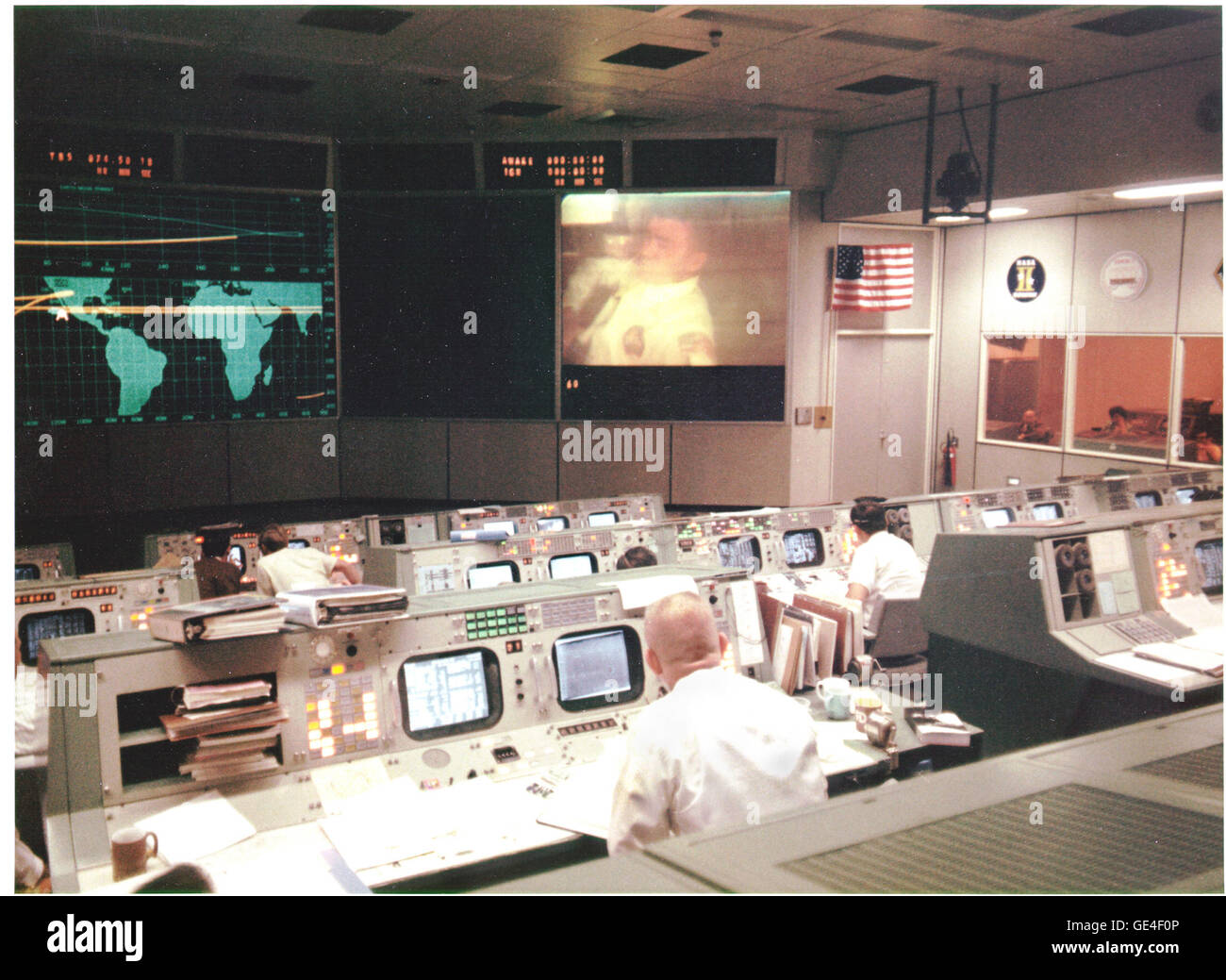 Overall view of the Mission Operations Control Room in the Mission Control Center at the Manned Spacecraft Center, during the fourth television transmission from the Apollo 13 spacecraft while en route to the Moon. Eugene F. Kranz (foreground, back to camera), one of four Apollo 13 Flight Directors, views the large screen at front of MOCR. Astronaut Fred W. Haise Jr., lunar module pilot, is seen on the screen. The fourth television transmission from the Apollo 13 mission was on the evening of April 13, 1970. Shortly after the transmission ended and during a routine procedure that required the  Stock Photo