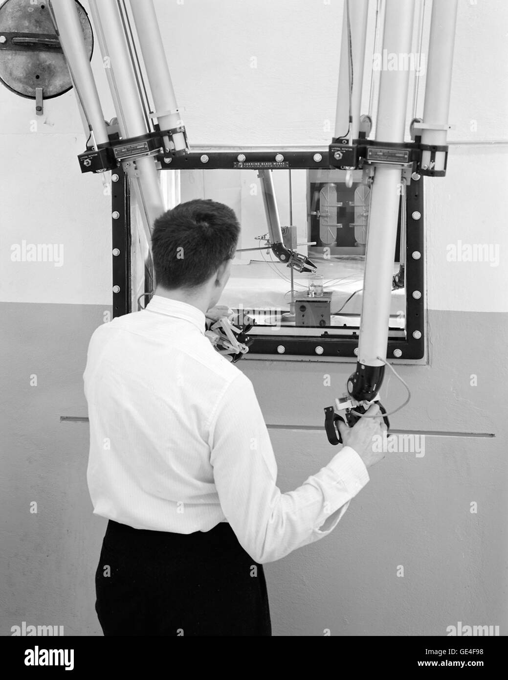 Bob Oldrieve, a hot laboratory supervisor, uses manipulator arms to inspect radioactive materials within a hot cell. The pliers-type &quot;hand&quot; is visible inside the window. Operators became so skillful in operating the manipulators that some were even able to thread a needle with them.   Image # : C-1961-55638 Stock Photo