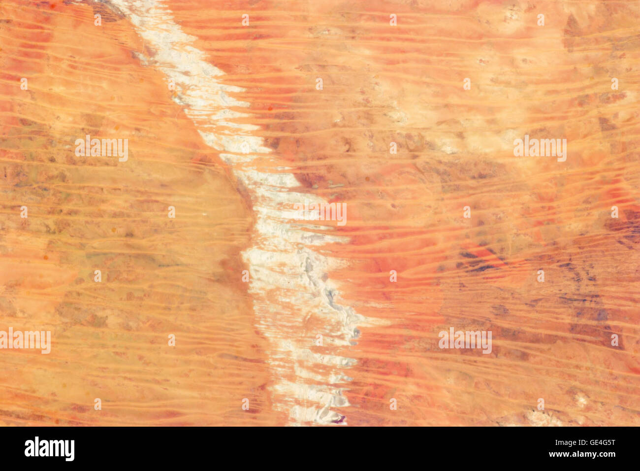 Description In northwest Australia, the Great Sandy Desert holds great geological interest as a zone of active sand dune movement. While a variety of dune forms appear across the region, this astronaut photograph features numerous linear dunes (about 25 meters high) separated in a roughly regular fashion (0.5 to 1.5 kilometers apart). The dunes are aligned to the prevailing winds that generated them, which typically blow from east to west. Where linear dunes converge, dune confluences point downwind. When you fly over such dune fields—either in an airplane or the International Space Station—th Stock Photo