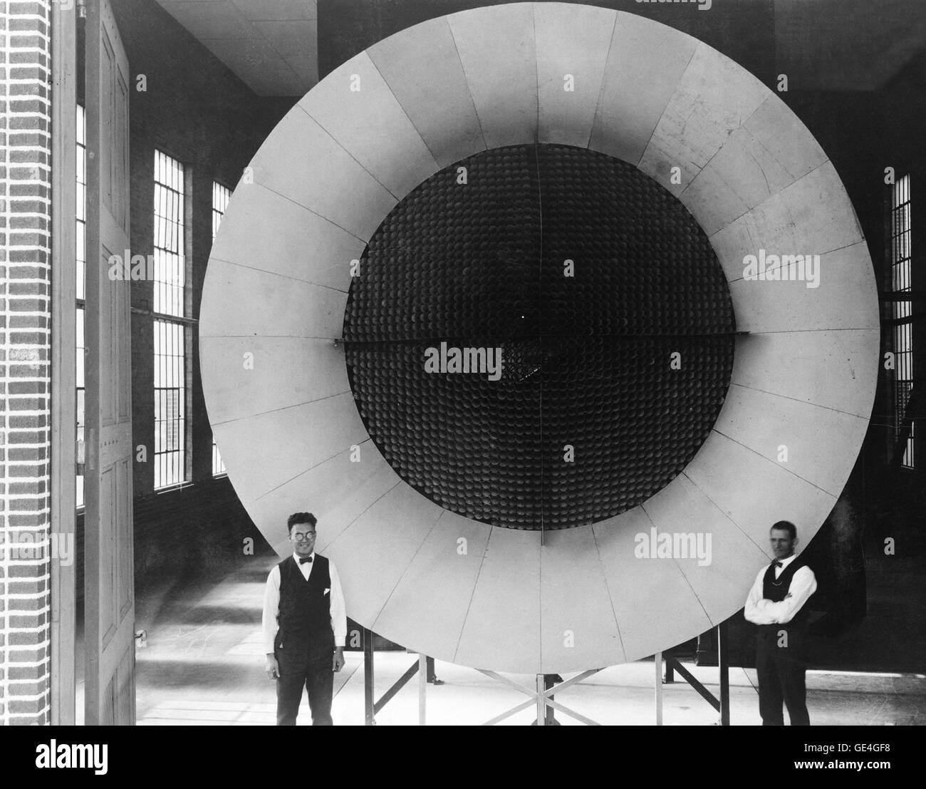 The honeycombed, screened center of this open-circuit air intake for Langley's first wind tunnel insured a steady, nonturbulent flow of air. Two mechanics pose near the entrance end of the actual tunnel, where air was pulled into the test section through a honeycomb arrangement to smoothen the flow. Stock Photo