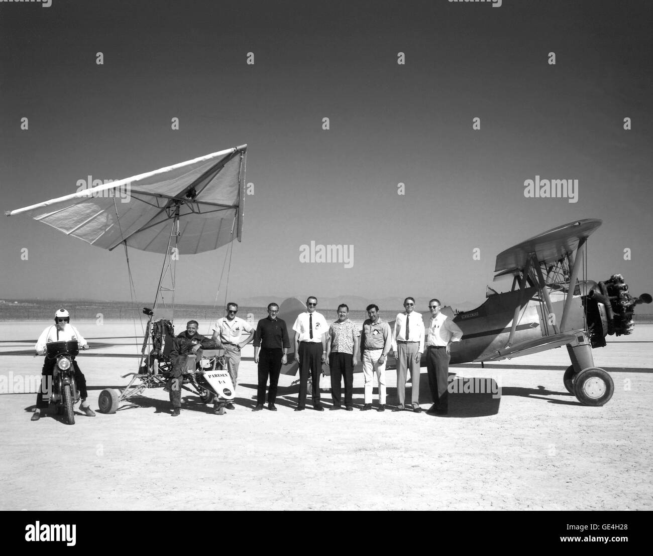 (August 24, 1962) With the Paresev 1-A and the 450-hp Stearman Sport Biplane as a backdrop the pilot and crew pose for this picture in 1962. Starting at left: On the motorcycle is Walter Whiteside, in the Paresev 1-A is test pilot Milton Thompson, Frank Fedor, Richard Klein, Victor Horton, Tom Kelly, Jr., Fred Harris, owner of the Stearman, John Orahood, and Gary Layton.  Image # : E-8713 Stock Photo