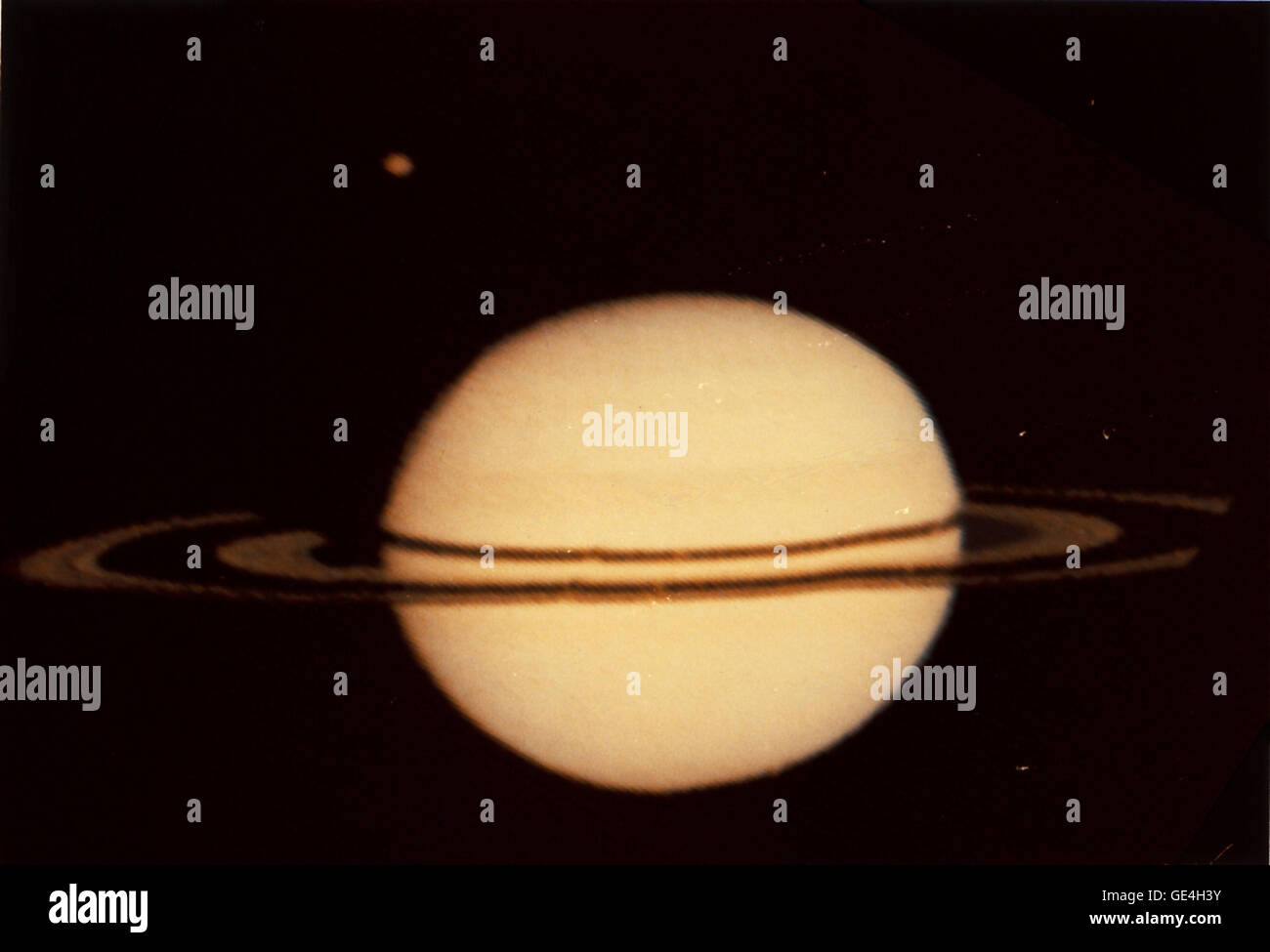 Description: (August 26, 1979) NASA's Pioneer 11 image of Saturn and its moon Titan at the upper left. The irregularities in ring silhouette and shadow are due to technical anomalies in the preliminary data later corrected. Looking at the rings from left to right, the ring area begins with the outer A ring; the Encke Division; the inner A Ring; Cassini Division; the B Ring; the C Ring; and the innermost area where the D Ring would be. The image was made by Pioneer Saturn on Wednesday, August 26, 1979, and received on Earth at 3:19 pm PDT. Pioneer was, at that time, 2,846,000 kilometers (1,768, Stock Photo