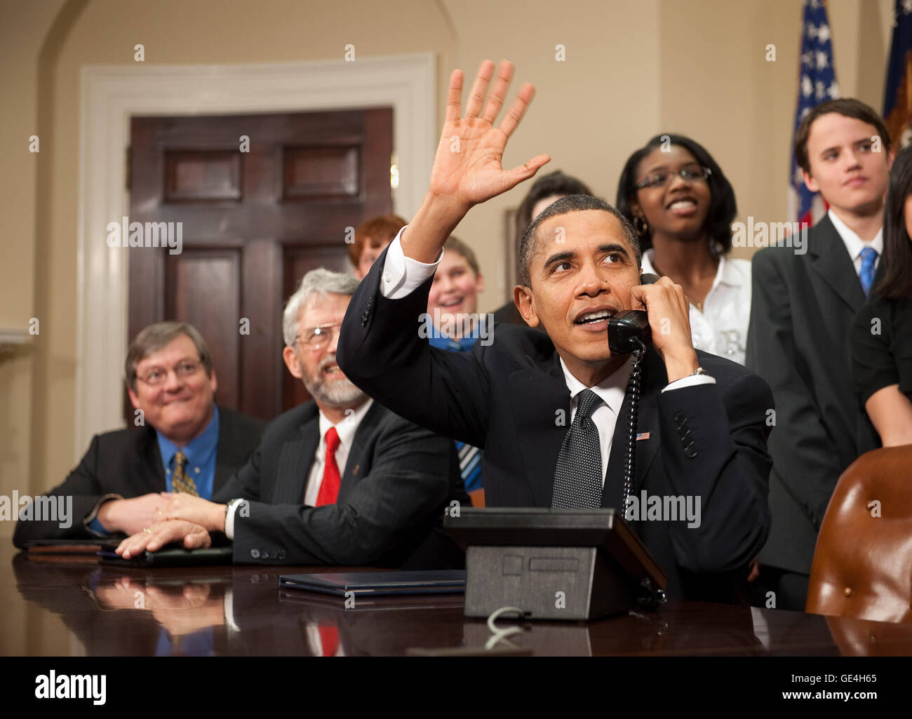 U.S. President Barack Obama, accompanied by members of Congress and middle school children,  waves as he talks on the phone from the Roosevelt Room of the White House to astronauts on the International Space Station, Wednesday, Feb. 17, 2010 in Washington.   Image #: 2010-02-17-0001Hq  Date: February 17, 2010 Photo Credit: (NASA/Bill Ingalls) Stock Photo