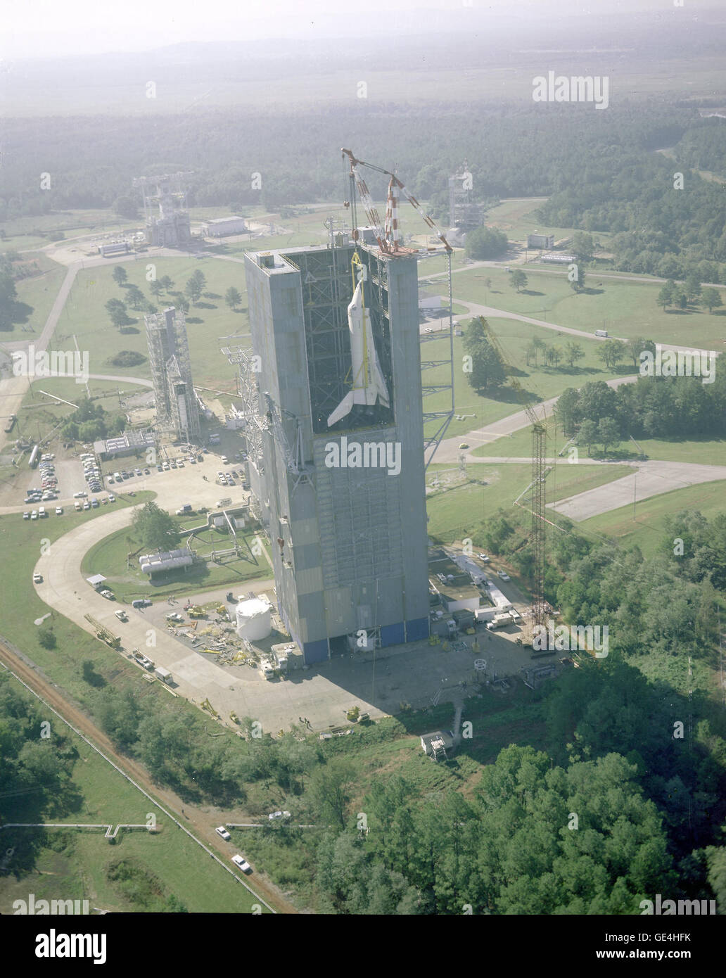 (October 4, 1978) Aerial view of Shuttle Orbiter Enterprise being hoisted into Marshall's Dynamic Test Stand for the Mated Vertical Ground Vibration test (MVGVT). The test marked the first time ever that the entire Space Shuttle elements, an Orbiter, an External Tank (ET), and two Solid Rocket Boosters (SRB), were mated together. Purpose of the vibration tests was to verify that the Space Shuttle performed its launch configuration as predicted.   Image # : 7992403 Stock Photo