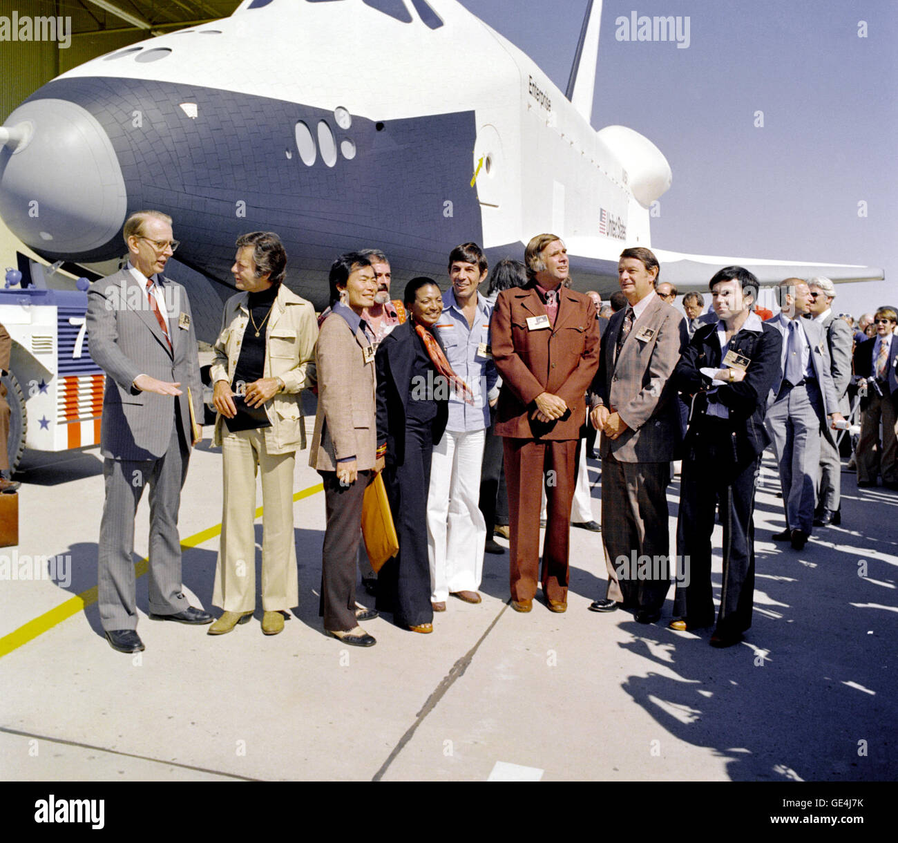 (September 17, 1976) The Shuttle Enterprise rolls out of the Palmdale manufacturing facilities with Star Trek television cast members. From left to right they are: Dr. James D. Fletcher, NASA Administrator, DeForest Kelley (Dr. &quot;Bones&quot; McCoy), George Takei (Mr. Sulu), James Doohan (Mr. Scott), Nichelle Nichols (Lt. Uhura), Leonard Nimoy (the indefatigable Mr. Spock), Gene Rodenberry (The Great Bird of the Galaxy), and Walter Koenig (Ensign Pavel Chekov).   Image # : S91-27436 Stock Photo