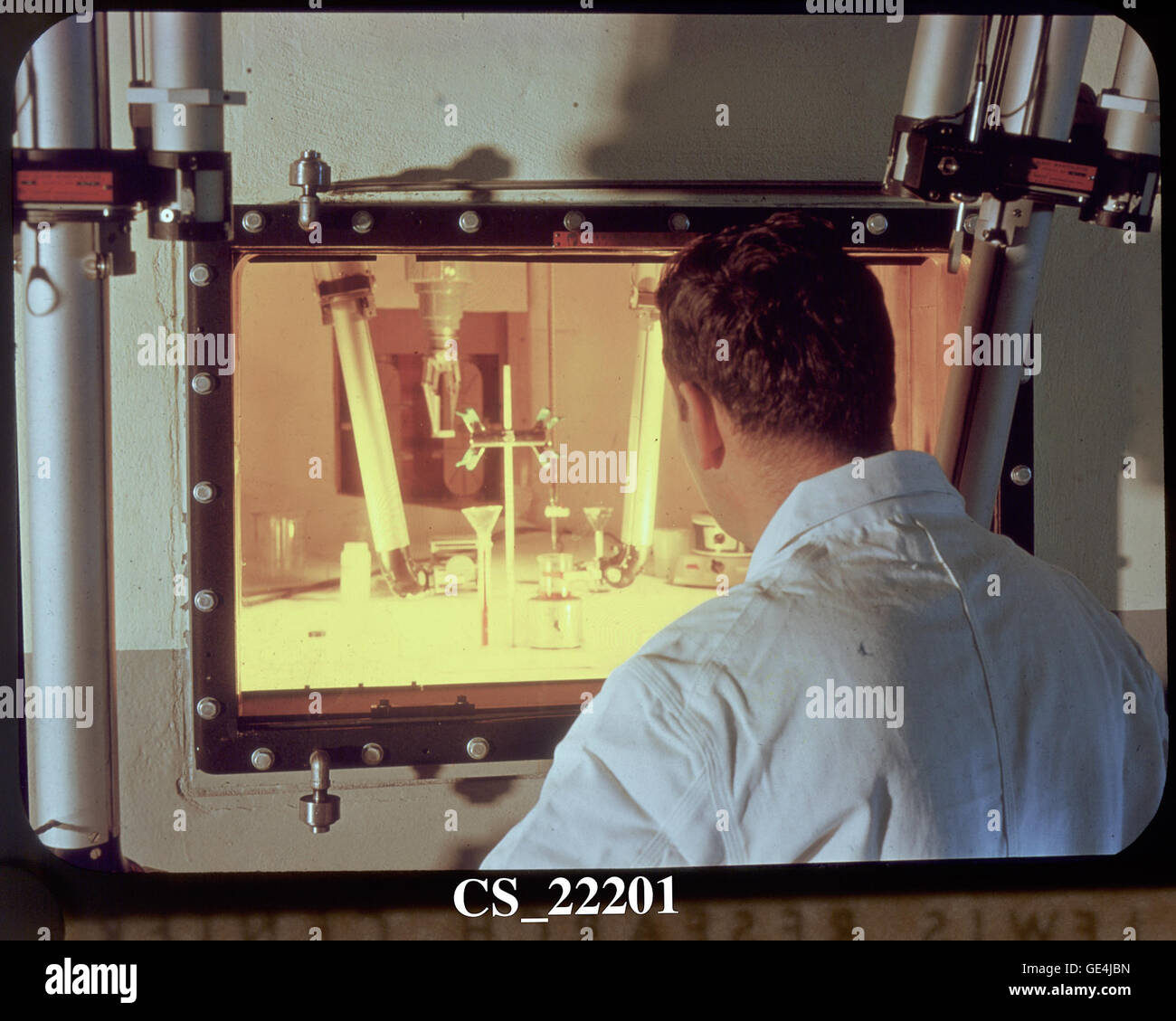 View into a hot laboratory. Technician Dan Gardner examines irradiated materials using remotely controlled manipulator arms from behind protective walls and shielded windows.  Image # : CS-22201 Stock Photo