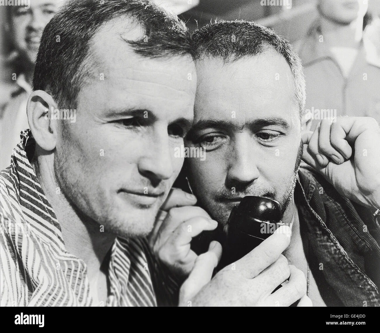 (June 7, 1965) Gemini 4 astronauts Edward H. White II (left) and James A. McDivitt listen to the voice of President Lyndon B. Johnson as he congratulated them by telephone on the successful mission. They are shown aboard the aircraft carrier U.S.S. Wasp just after their splashdown recovery from the Atlantic Ocean.   Image # : S65-33533 Stock Photo