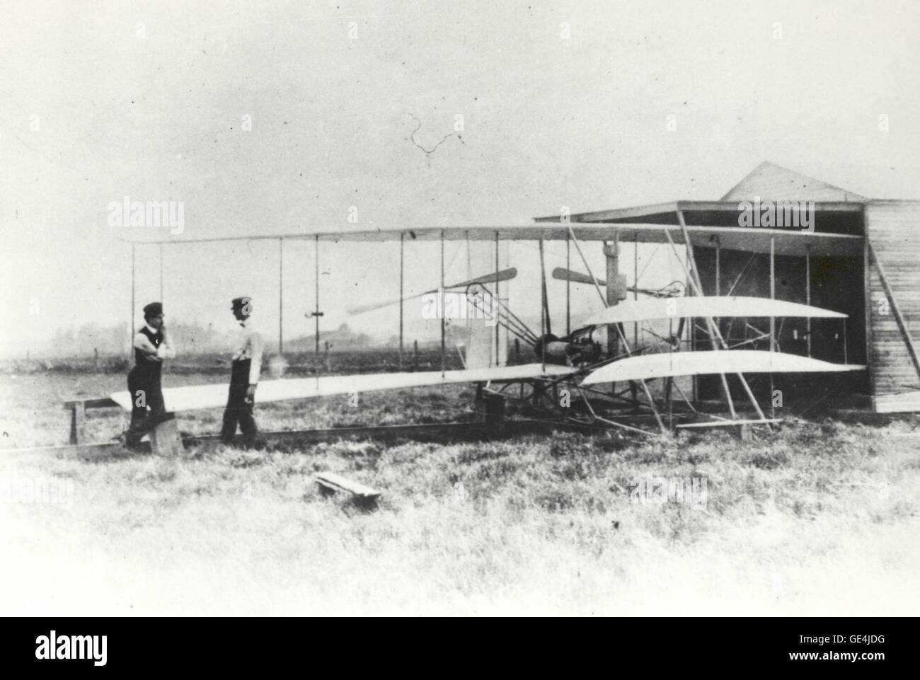 (May 1, 1904) Wilbur and Orville Wright with the Flyer II at Huffman Prairie, outside of Dayton, Ohio, on May 1, 1904.   The Wrights had a much more difficult time testing their aircraft at Huffman Prairie than at Kill Devil Hills, North Carolina, due to the lack of high winds. To artificially reach the needed wind speed of 27 miles per hour, the brothers invented a catapult which provided the extra speed needed to become airborne. On September 7, 1904, the Wrights tested the first catapult and it was a success, giving the Flyer II a push to make half-mile long flights.  Image # : wrightflyer- Stock Photo
