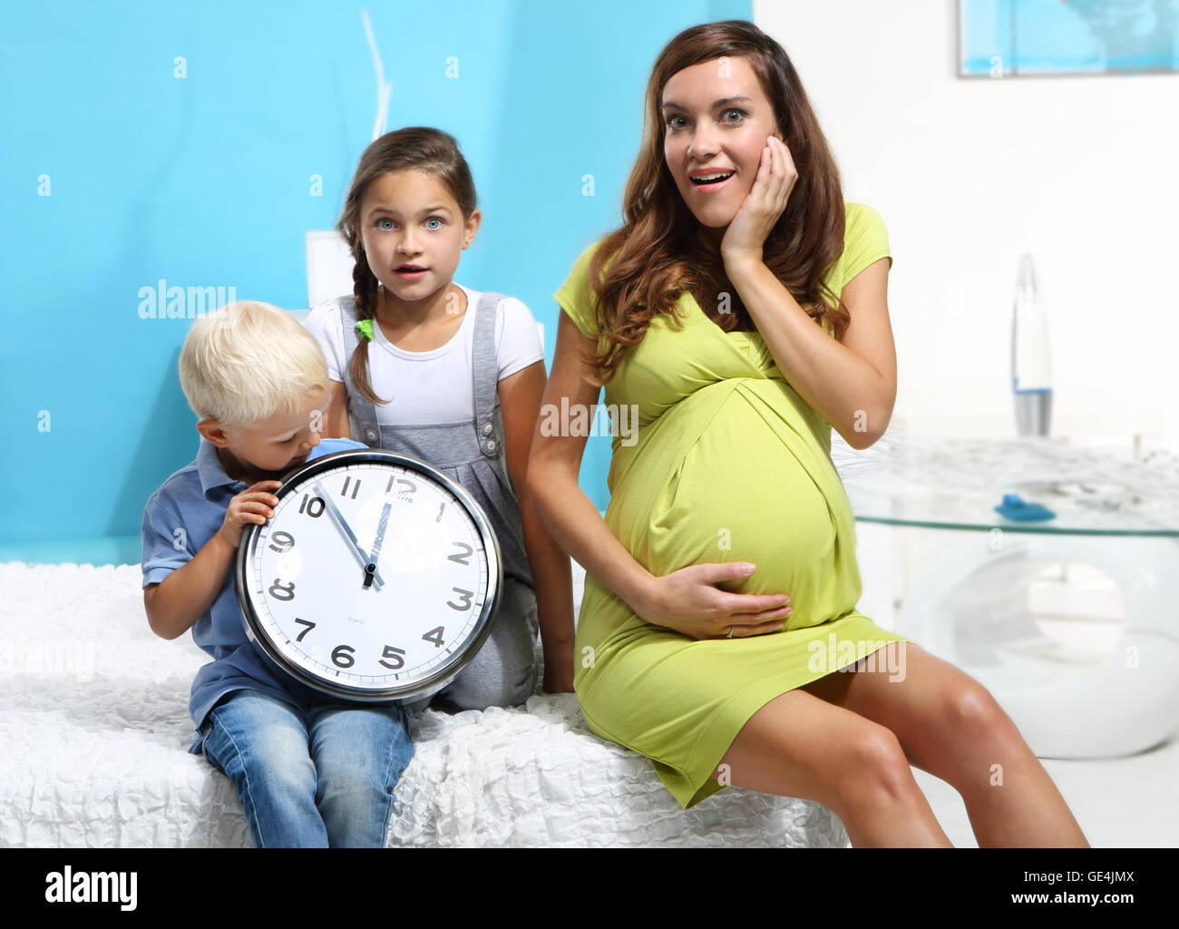 Pregnant mother and children with a clock. Stock Photo