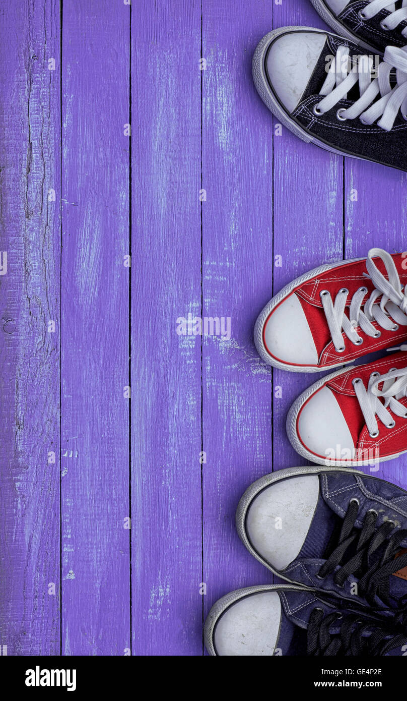 Three pairs of sneakers on a purple wooden background Stock Photo - Alamy