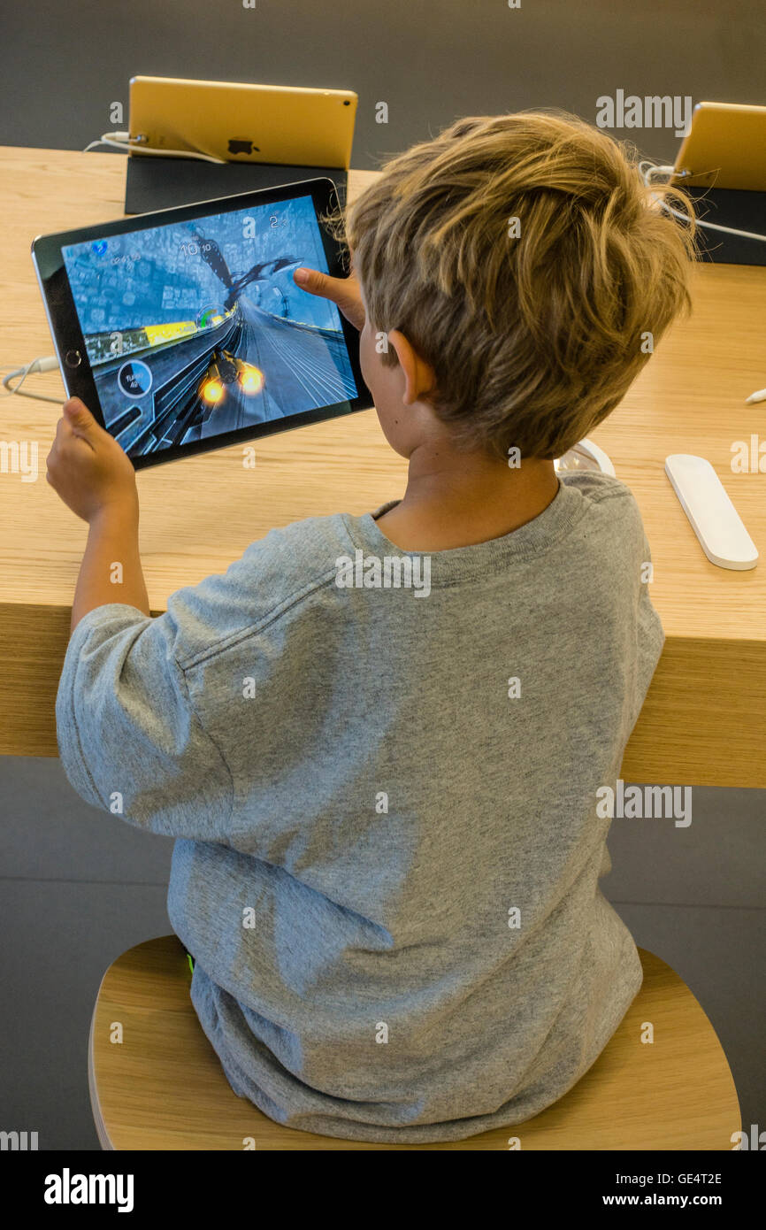 A young boy 7-8 years old plays a game on an iPad at the Apple Store in Santa Barbara, California. Stock Photo