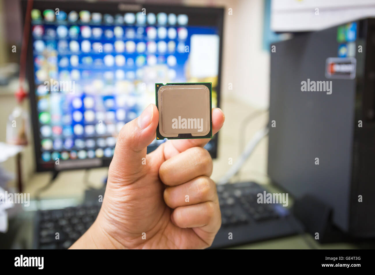 CPU in hand with desktop PC computer at office background. soft focus Stock Photo