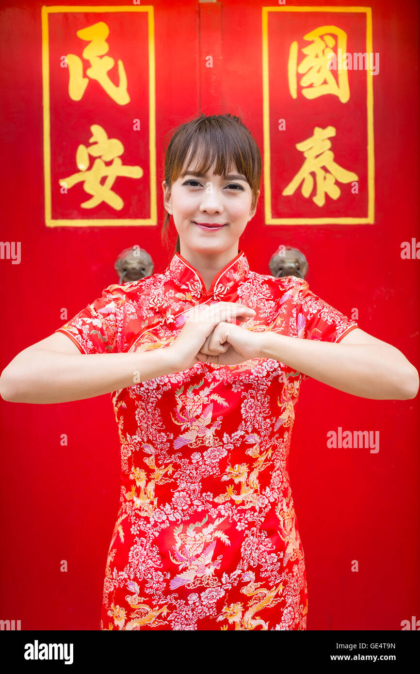 Happy Chinese new year. Cute Asian woman with gesture of congratulation isolated on red chinese pattern traditional background Stock Photo