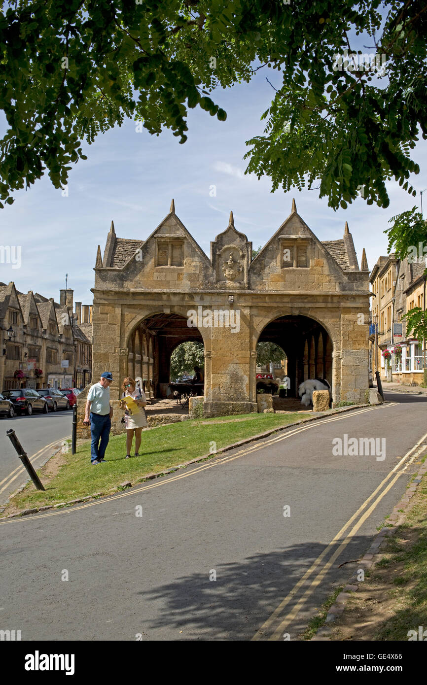 Two people looking at map outside Cotswold stone market hall Chipping Campden erected in 1627 Cotswolds UK Stock Photo