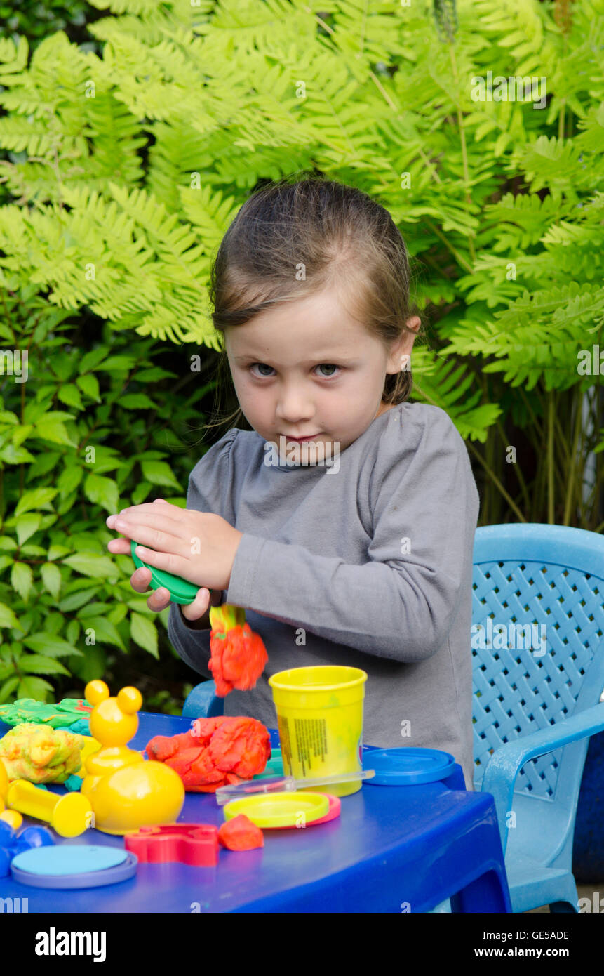 Three year old girl play with PlayDoh modeling putty. UK. Outside in