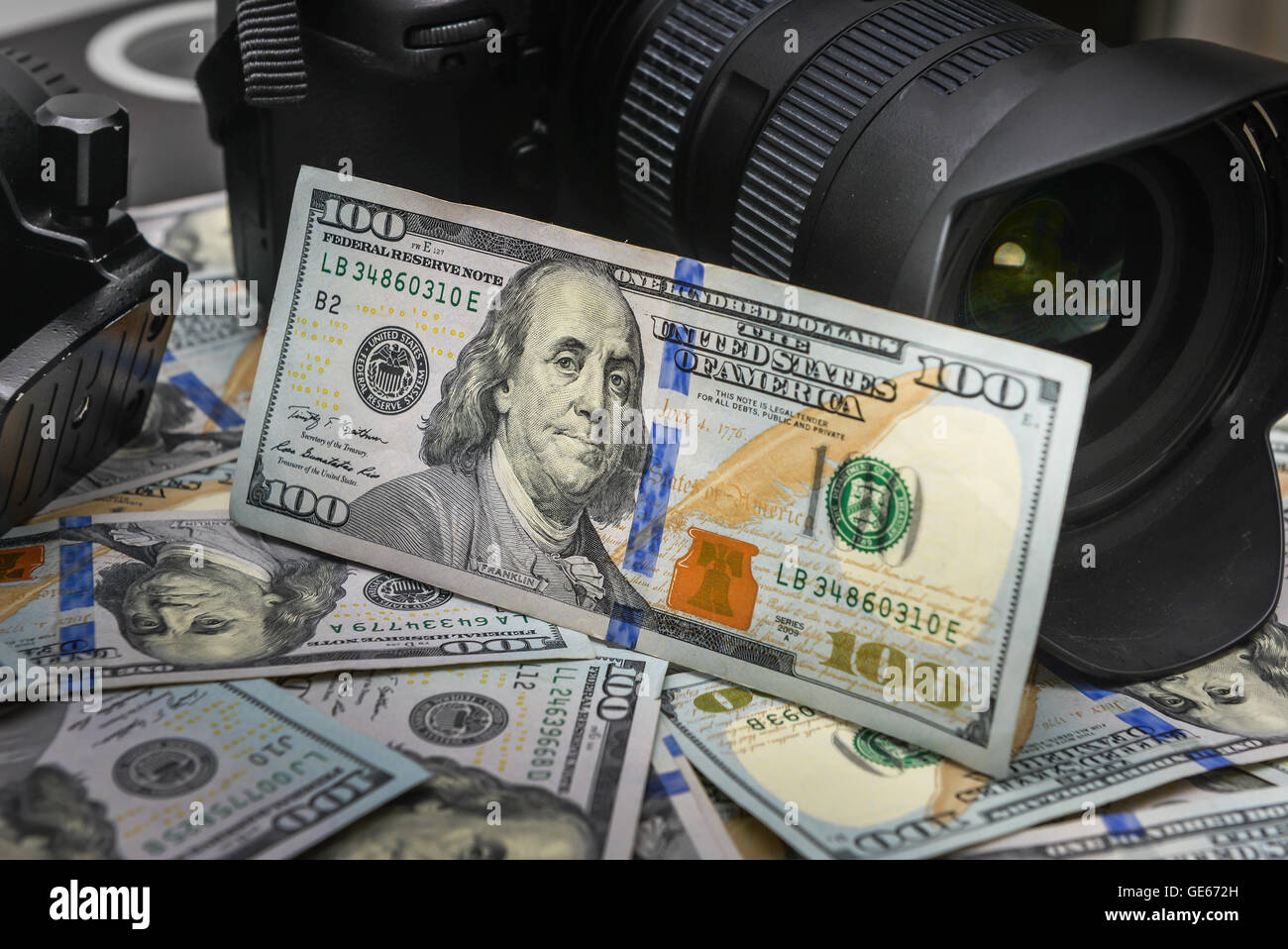 Background American one hundred dollar bills and DSLR camera devices. Making a lot of money by DSLR camera, Success business con Stock Photo
