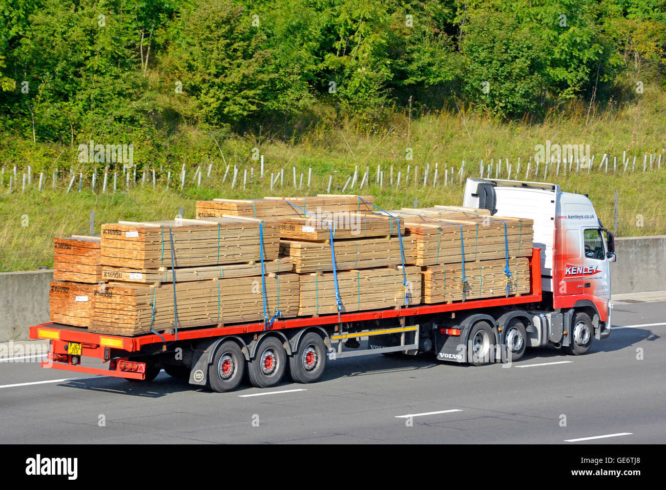Construction materials supply chain transportation logistics via Hgv articulated lorry & trailer loaded with timber driving along UK English motorway Stock Photo