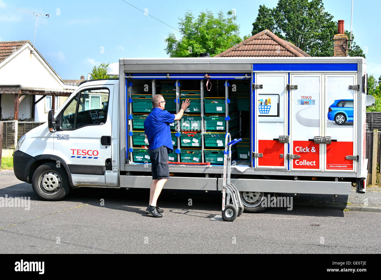 Tesco Supermarket home delivery van driver unloading groceries onto trolley at customers street address in residential road Essex England UK Stock Photo