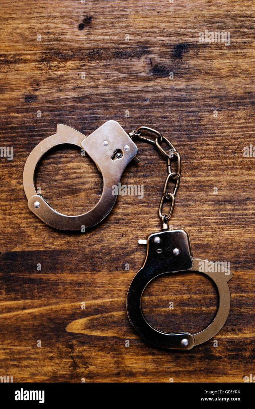 Police handcuffs on investigator detective's work desk, concept of law and crime. Stock Photo