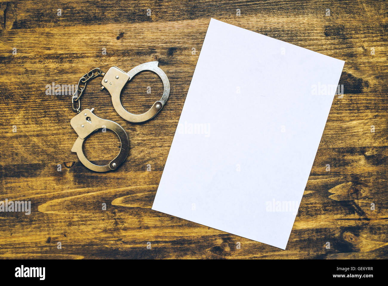 Police handcuffs and blank paper on investigator detective's work desk, concept of law and crime. Stock Photo