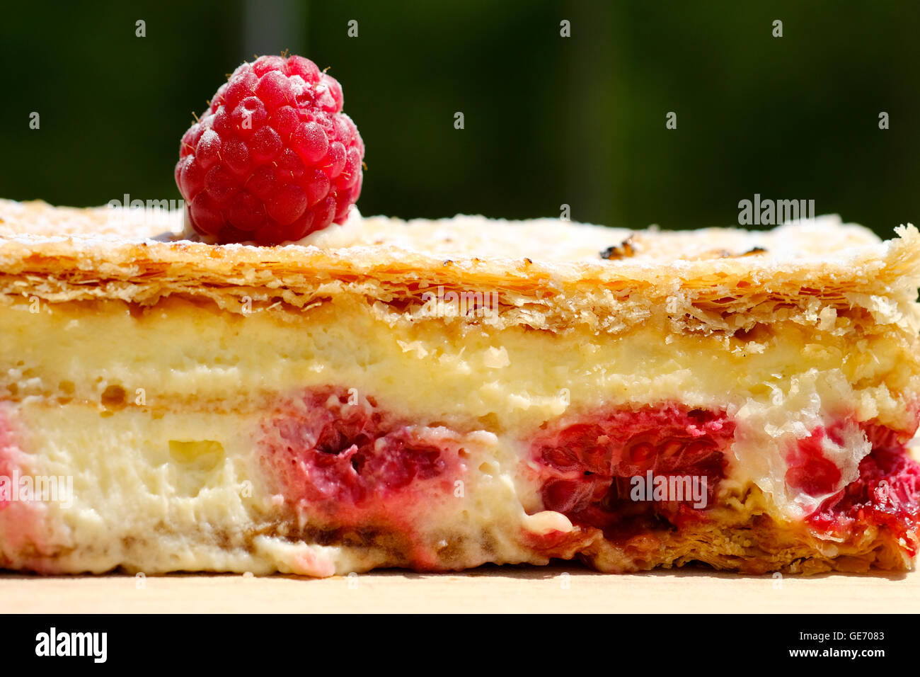 A tasty delicious looking fresh raspberry, puff pastry, cream slice cake decorated with a raspberry on top Stock Photo