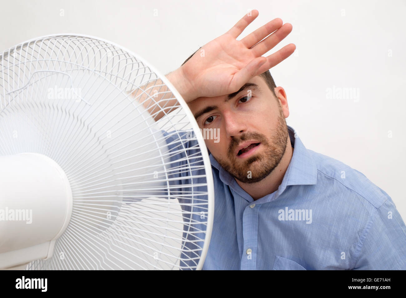 Flushed man feeling hot in front of a fan Stock Photo Alamy