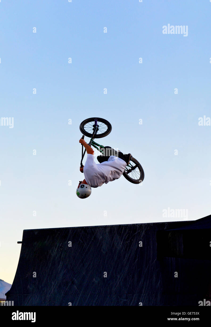 A person doing a back flip over a jump on a BMX bicycle Stock Photo
