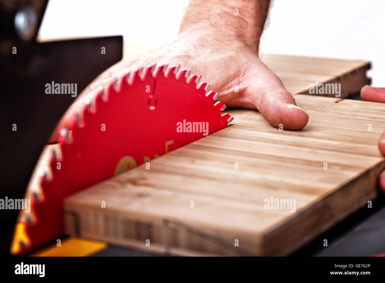 detail of table saw blade and human hand in dangerous position Stock Photo