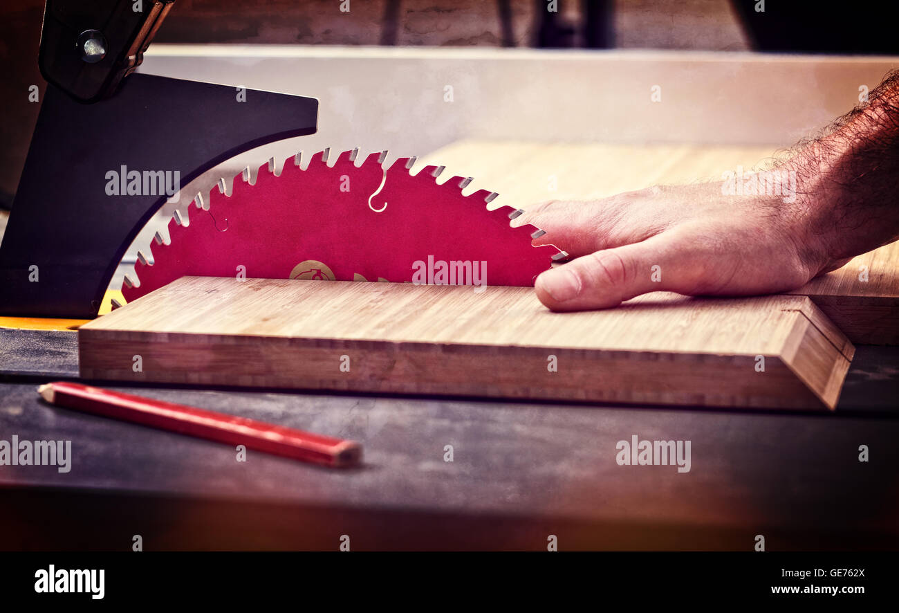 detail of table saw blade and human hand in dangerous position Stock Photo