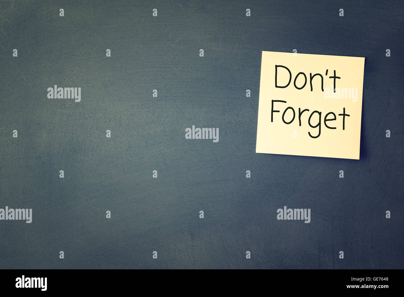 don't forget reminder, written on sticky memo attached to blackboard ...